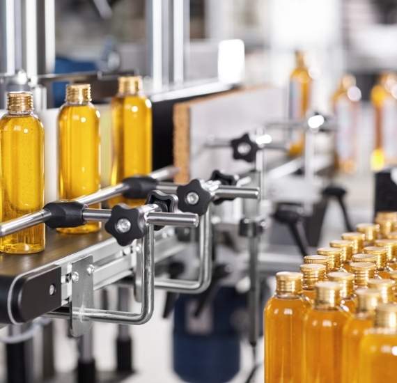 Image of orange coloured bottles being filled by an automated machine.